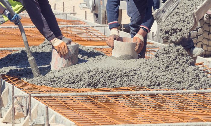 A group of construction workers are pouring concrete on a construction site.