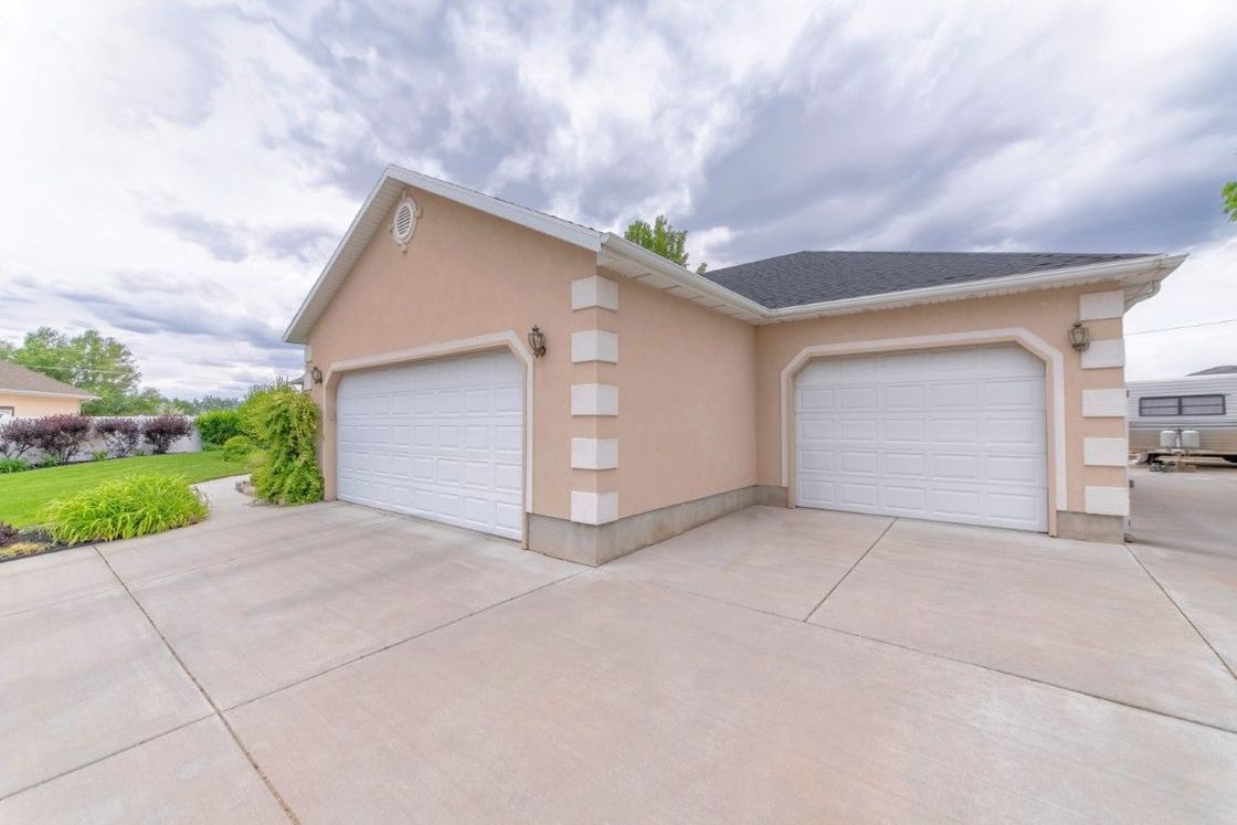 A house with two garage doors and a trailer parked in front of it.