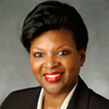 A woman in a suit and red lipstick is smiling for the camera.