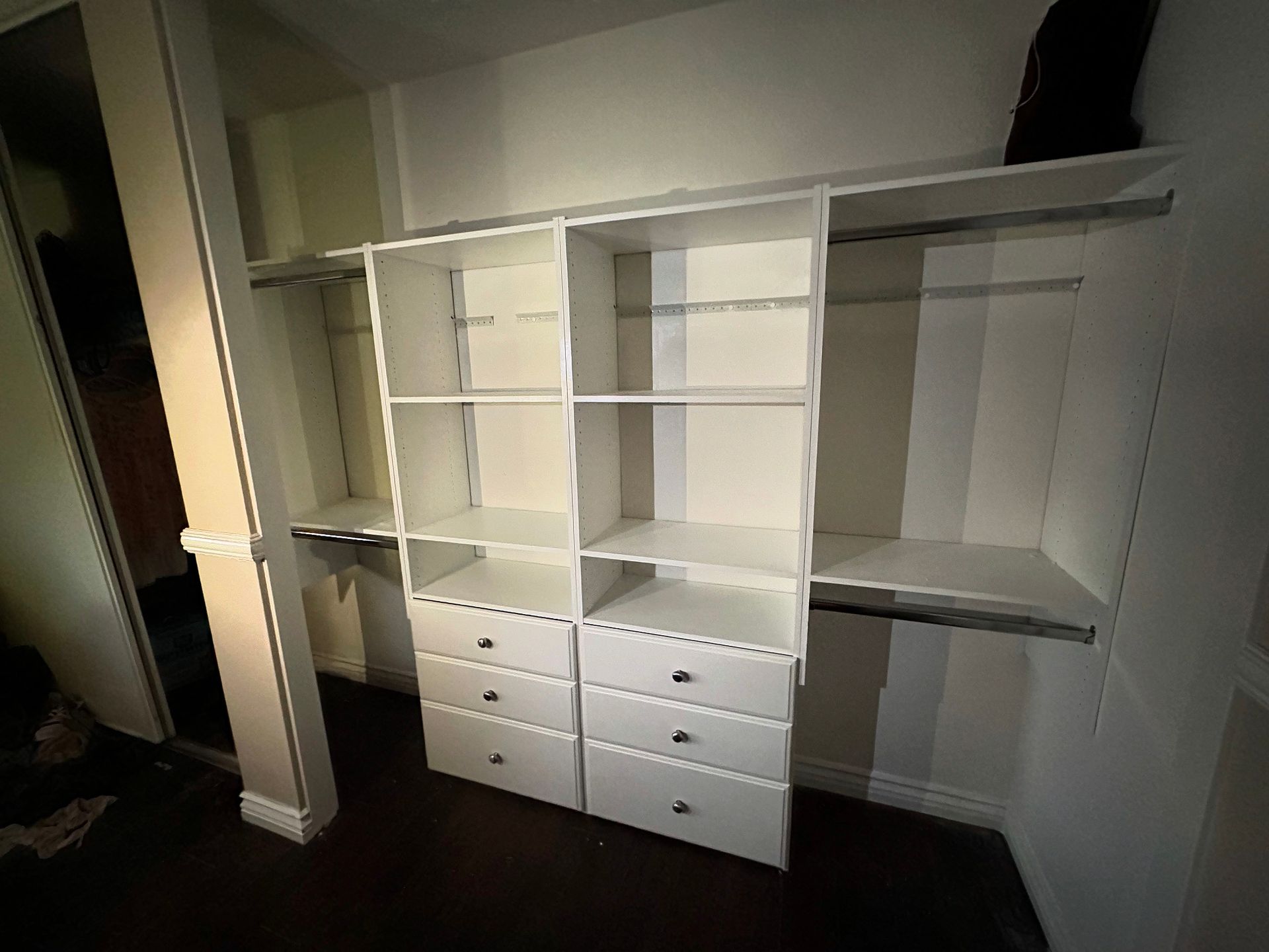 White closet organizer with shelves, drawers, and hanging rods.