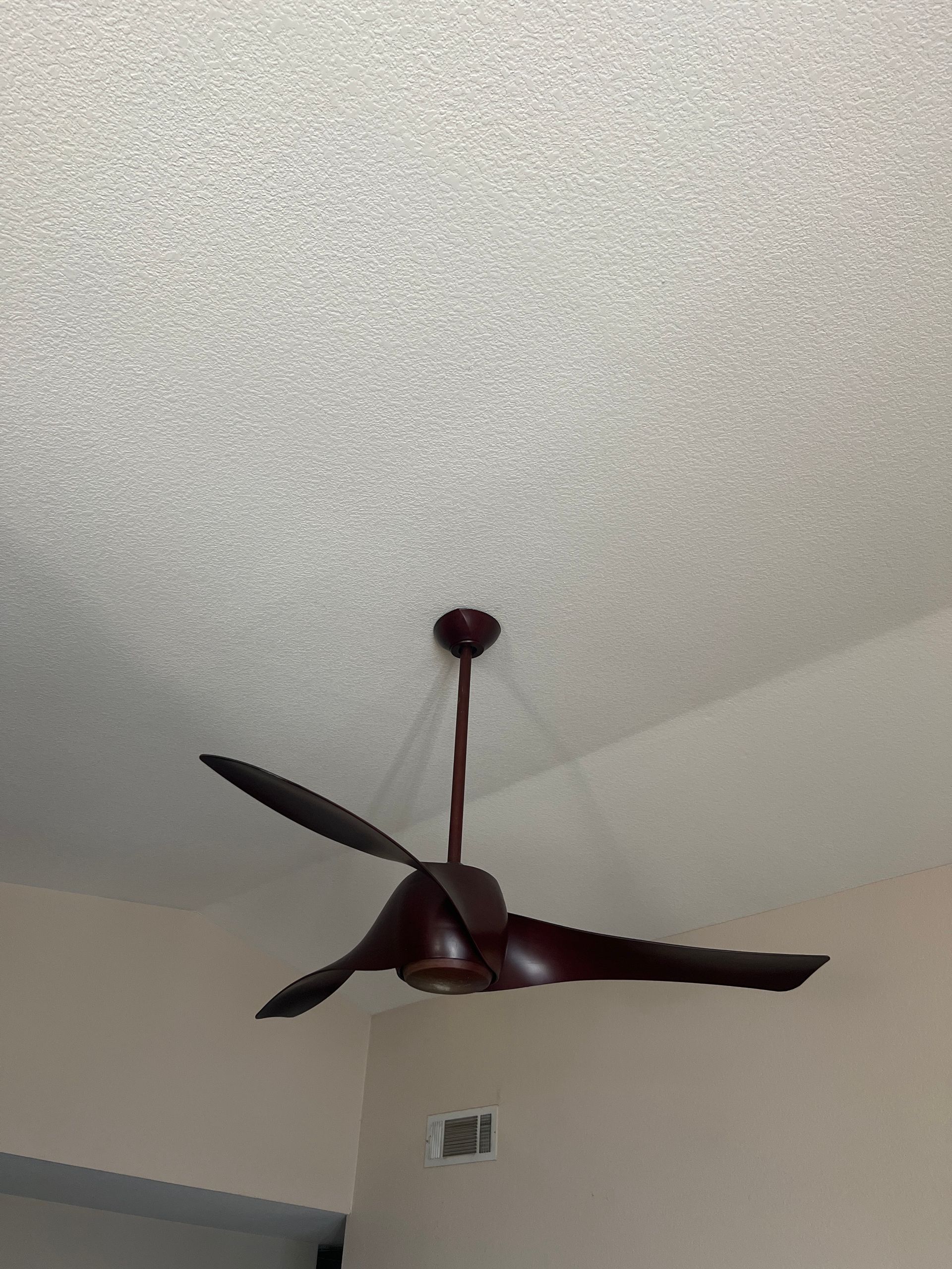 Ceiling fan with dark brown blades against a textured white ceiling.