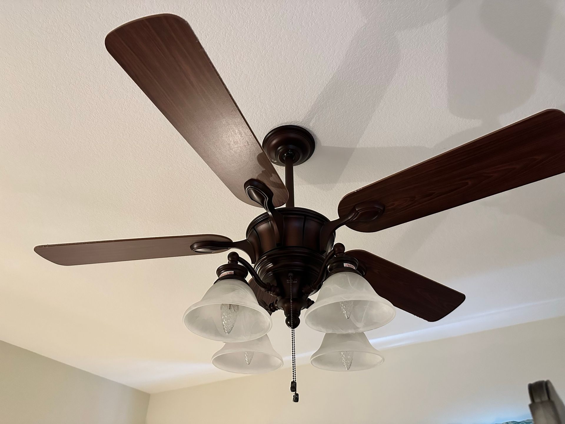Ceiling fan with brown blades and frosted glass light fixtures.