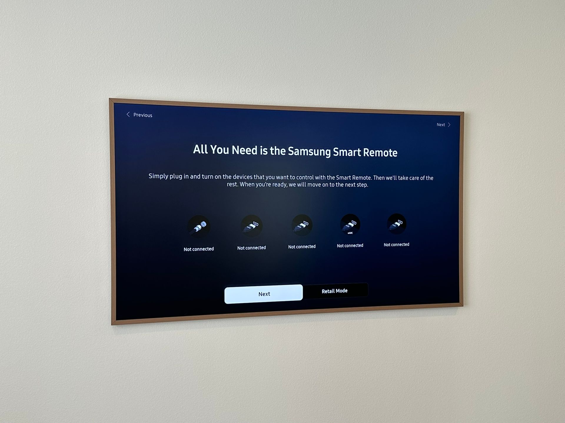 A wall-mounted TV displaying a smart device setup screen, with text and icons, against a light-colored wall.