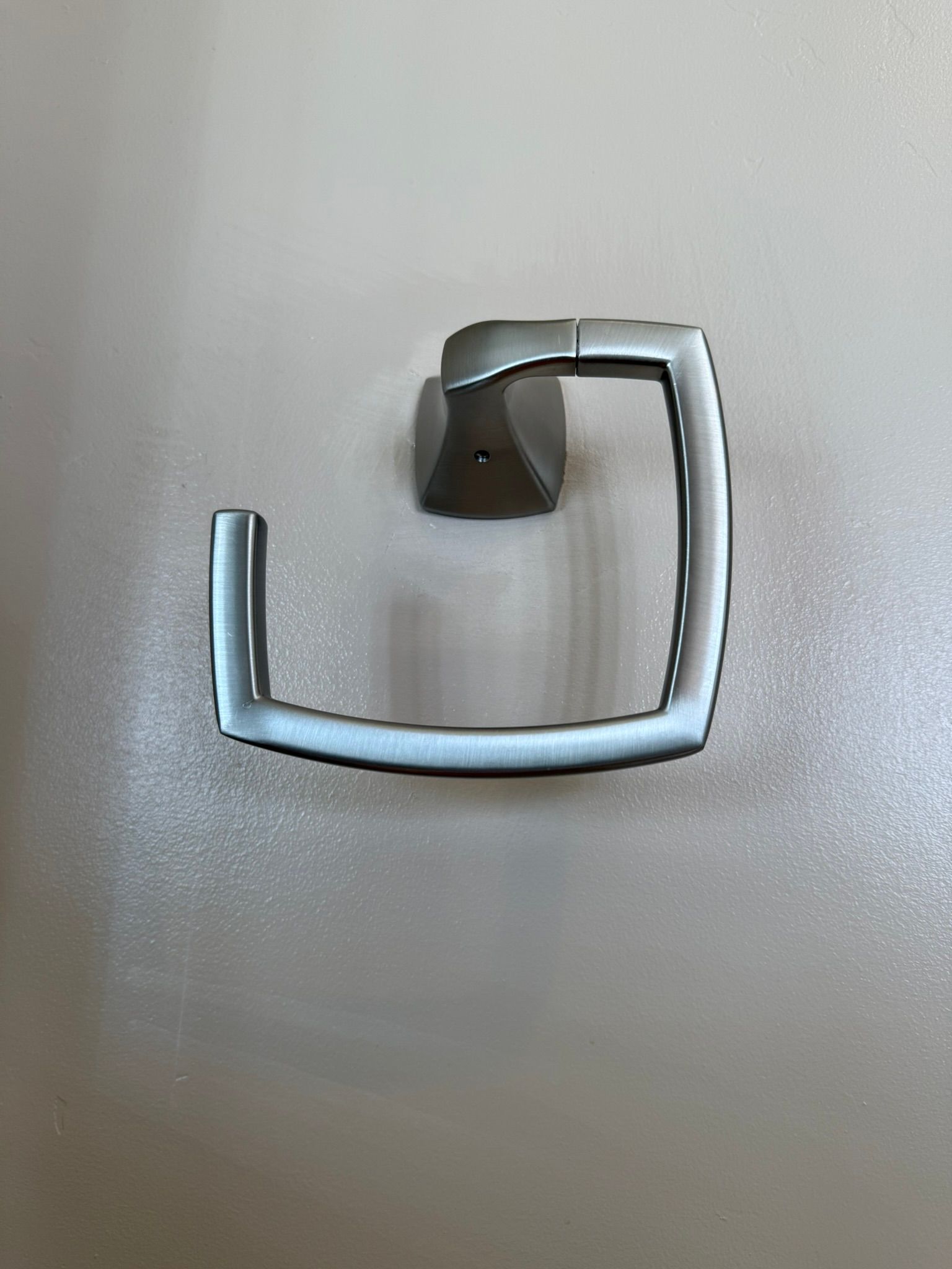 Close-up of a silver metal towel hook on a plain gray wall