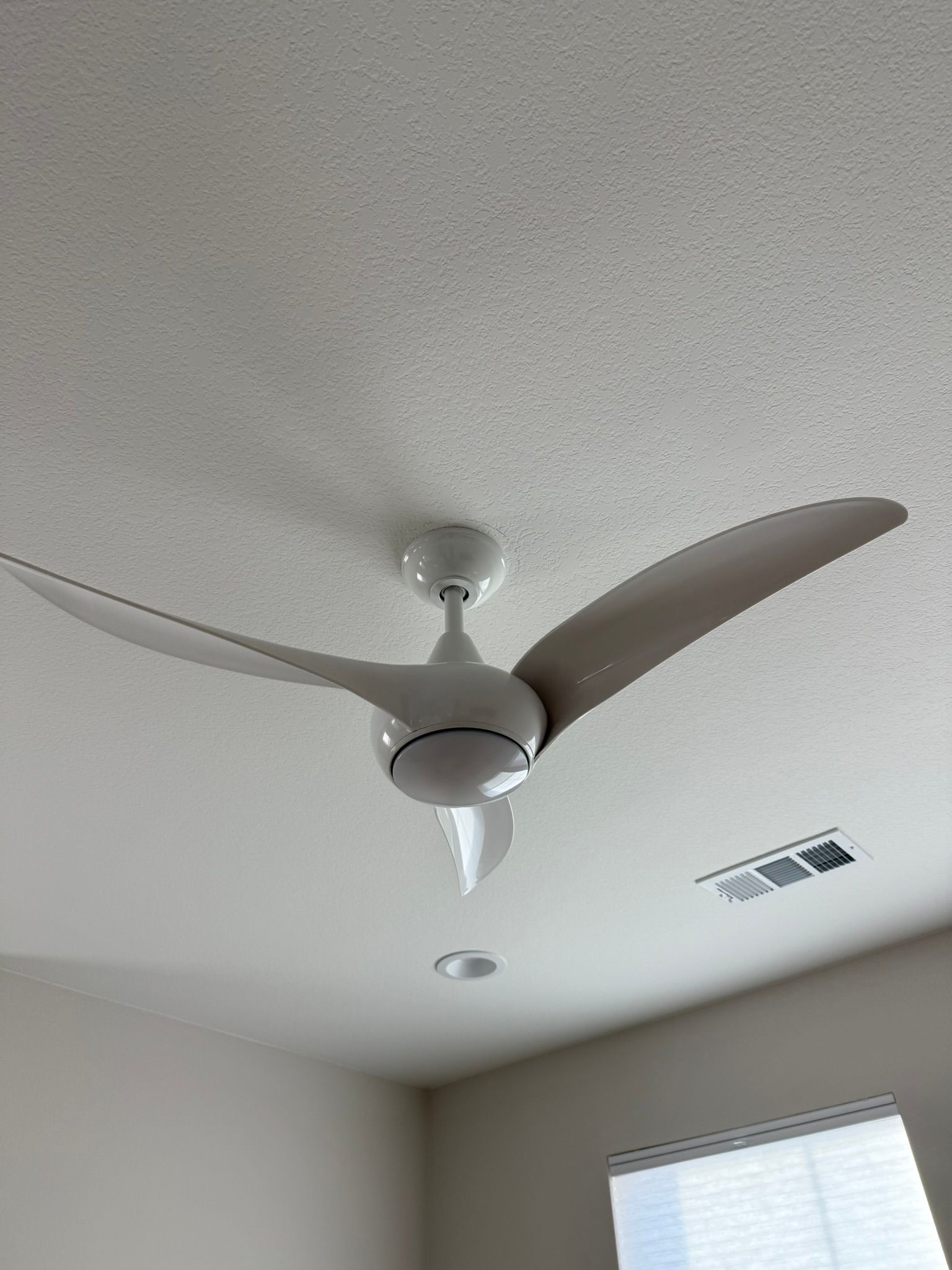 White ceiling fan with three curved blades, centered on a textured white ceiling.
