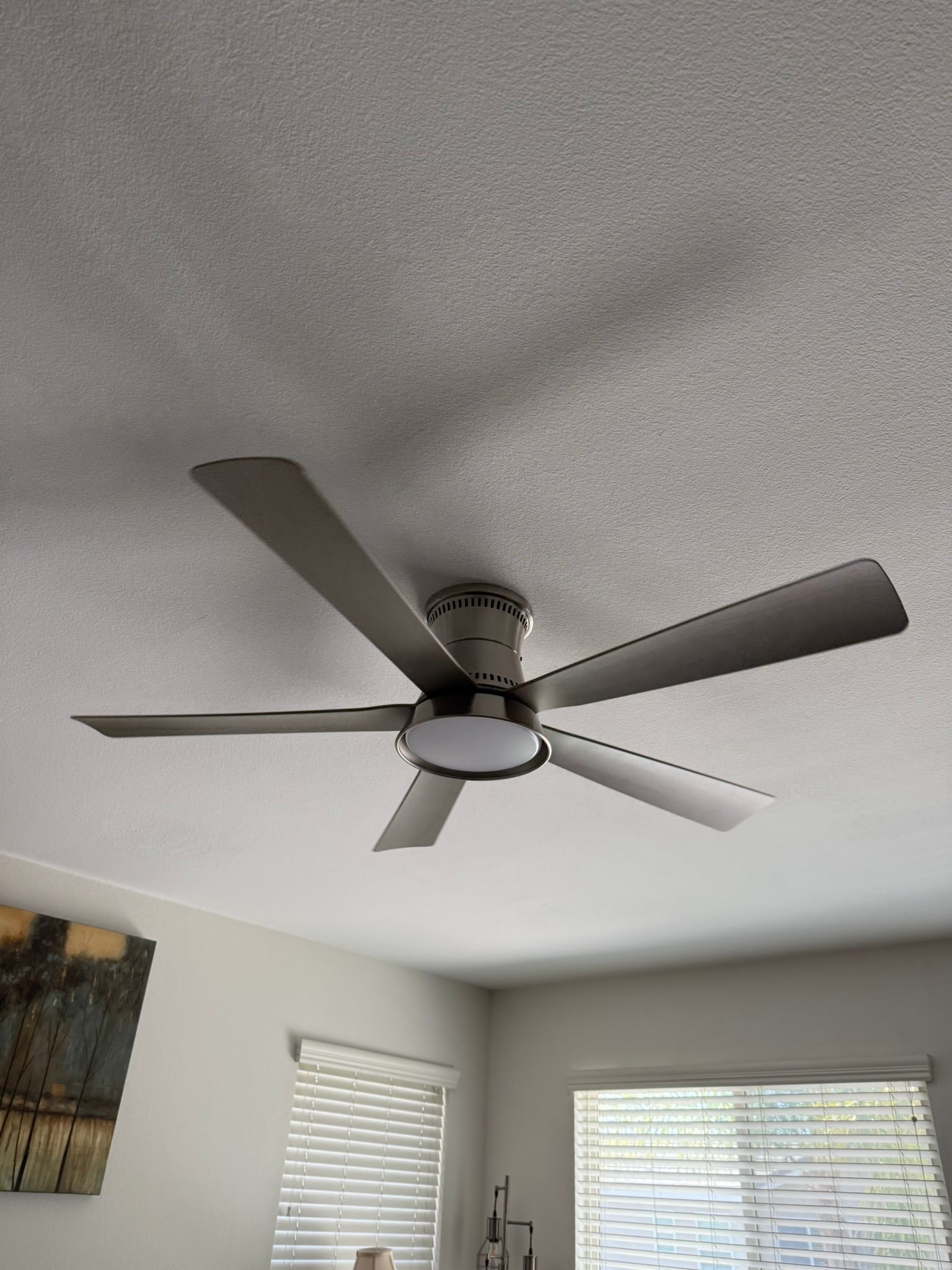 Ceiling fan with five blades, light fixture, mounted on textured white ceiling.