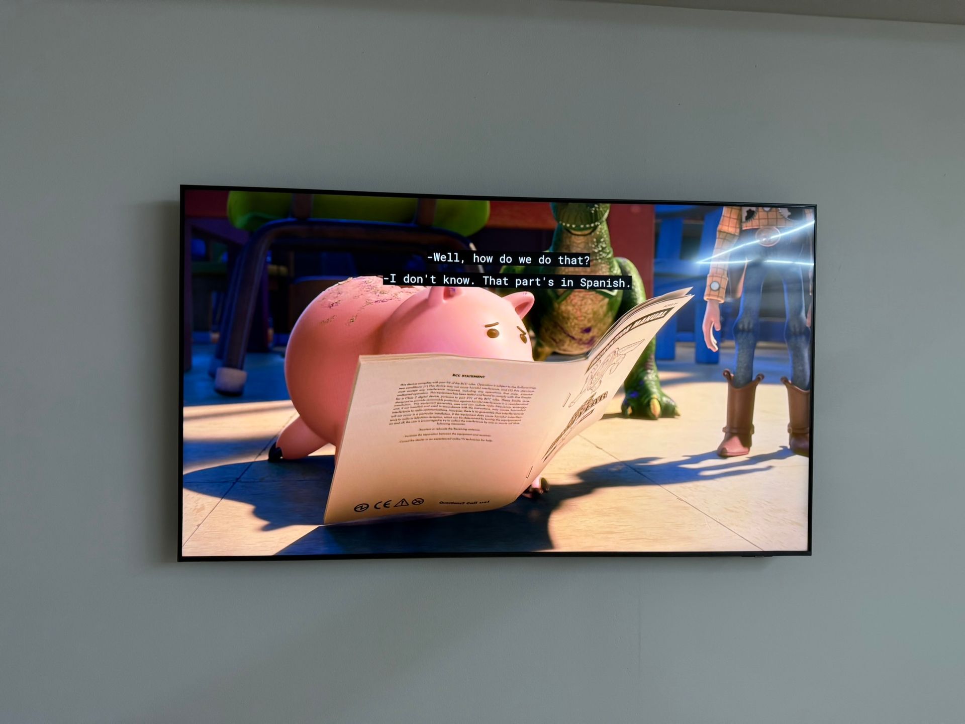 A scene from Toy Story on TV: Hamm the piggy bank reads music, Rex the dinosaur stands by.
