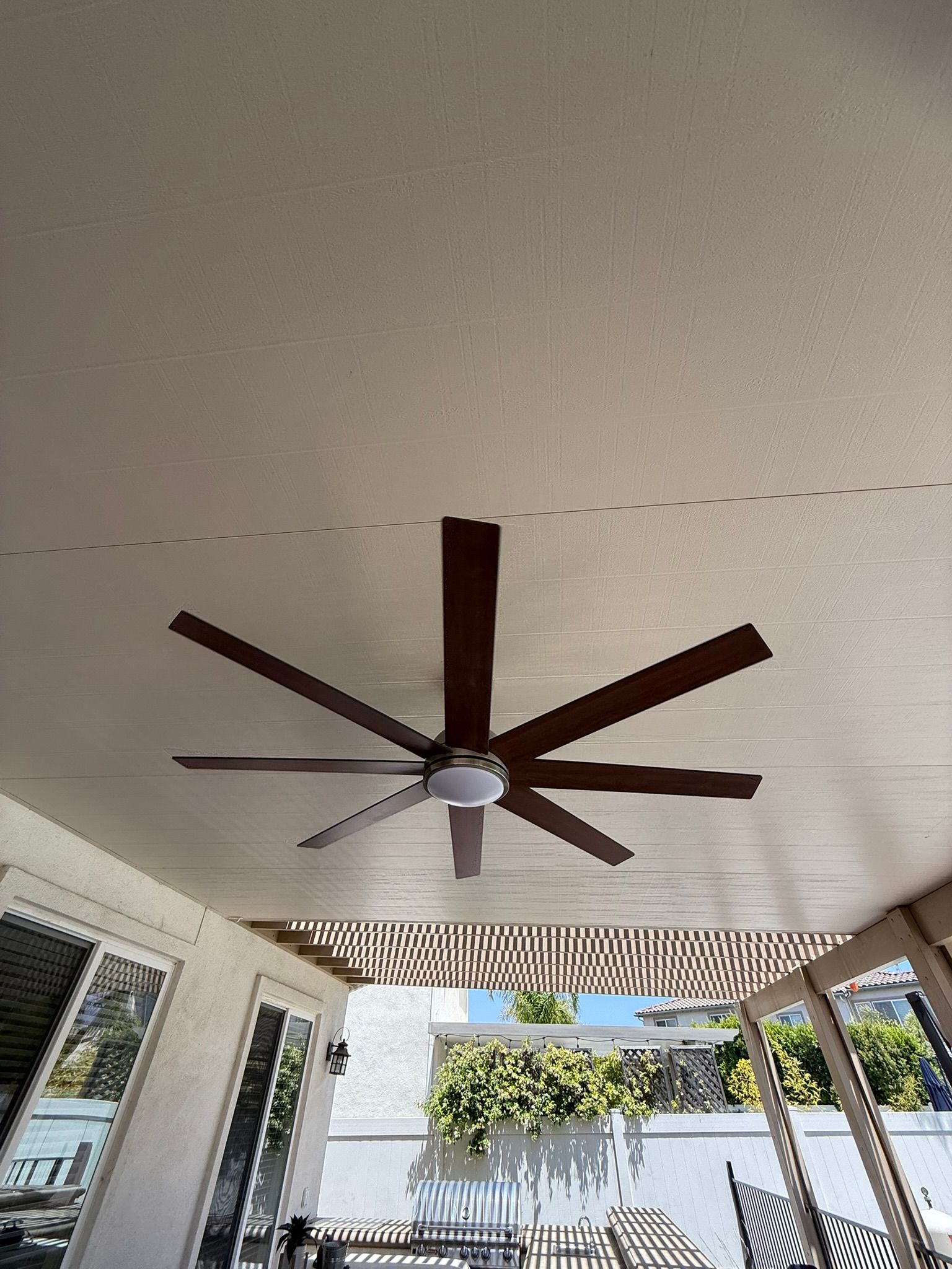 Ceiling fan with dark brown blades, centered on a light-colored patio ceiling.