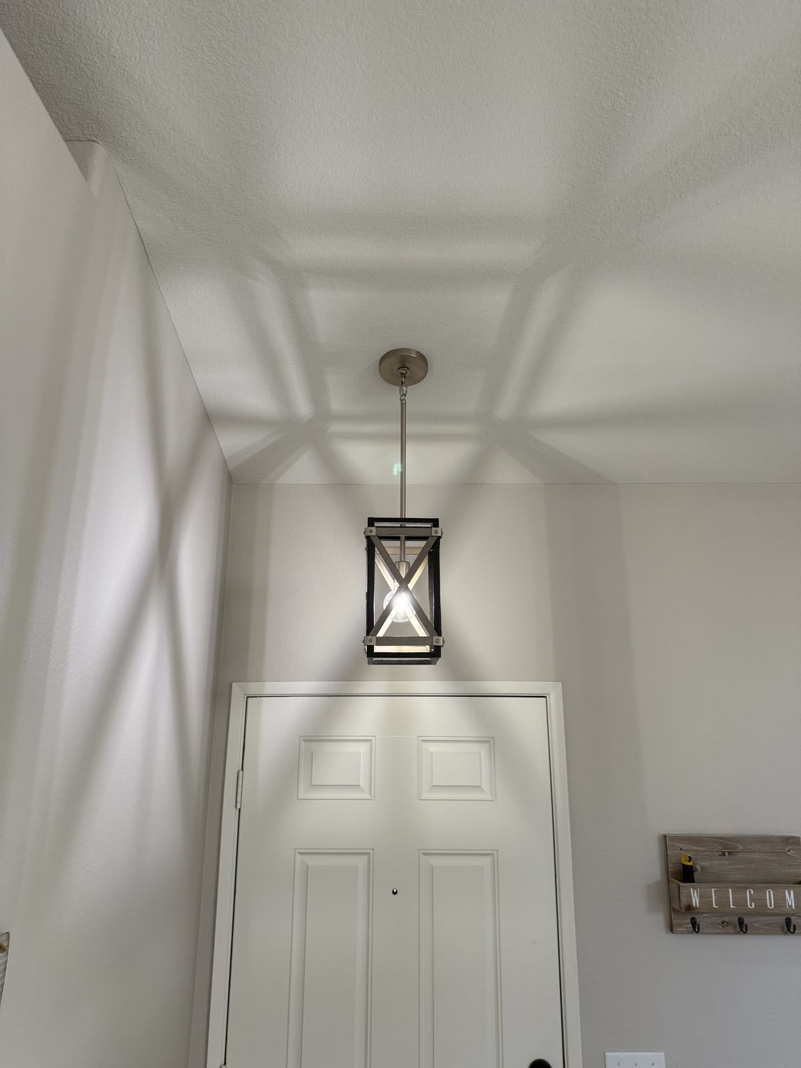 Ceiling light fixture above a white door; shadows cast on the ceiling.