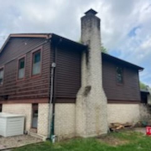 Exterior of a brown-sided house with a large, light-colored brick chimney.