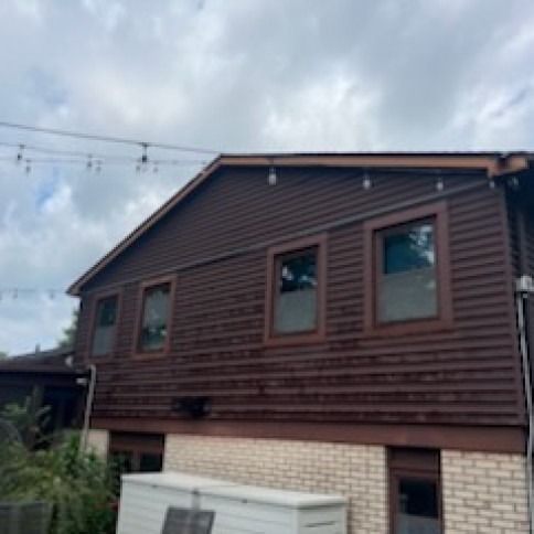 Brown house exterior with windows, string lights, and a white storage box.