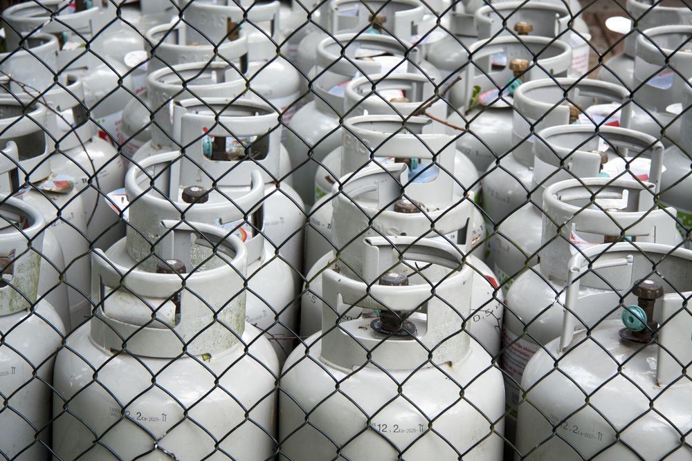 Rows of White Propane Tanks Behind a Chain-link Fence  Dunnrite Plumbing Services in Proserpine, QLD 