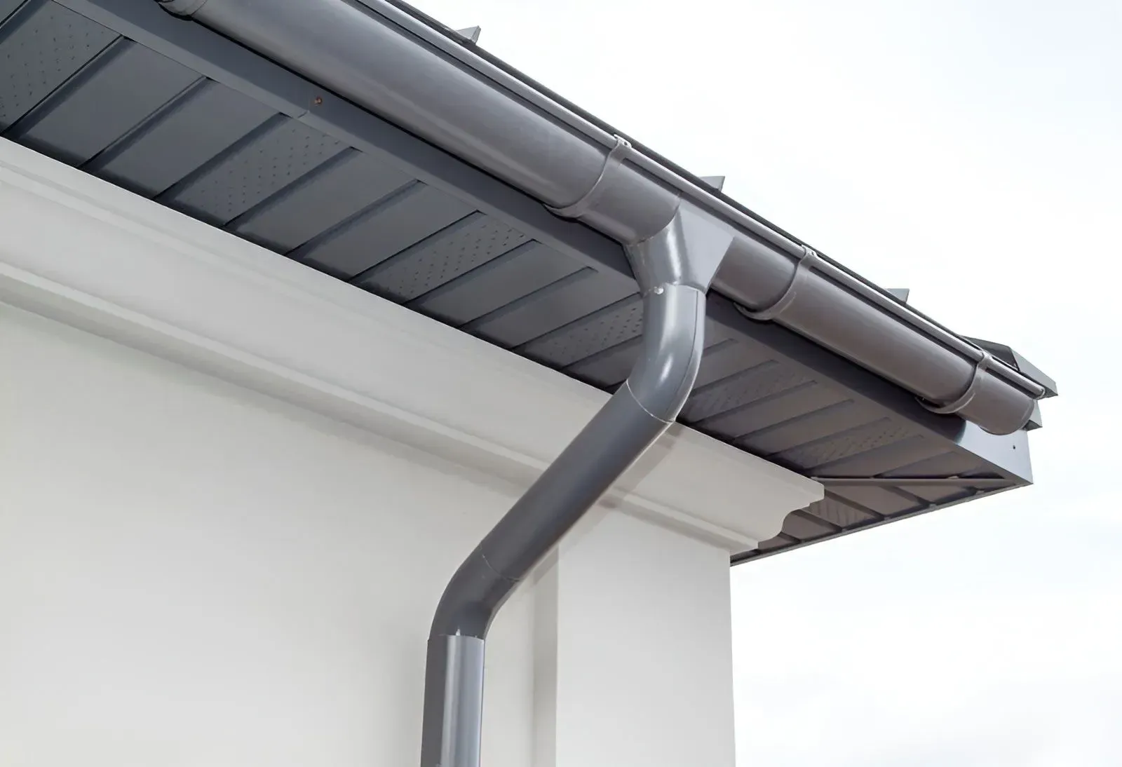 A Grey Metal Gutter and Downspout Attached to the Side of Roof — Dunnrite Plumbing Services in Airlie Beach, QLD