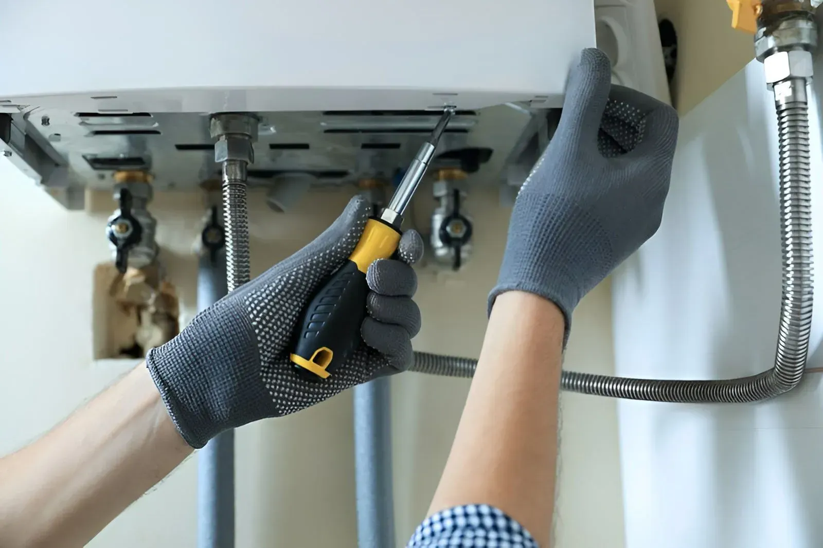 A Person  Uses a Screwdriver to Repair or Install Gas Water Heater — Dunnrite Plumbing Services in Airlie Beach, QLD