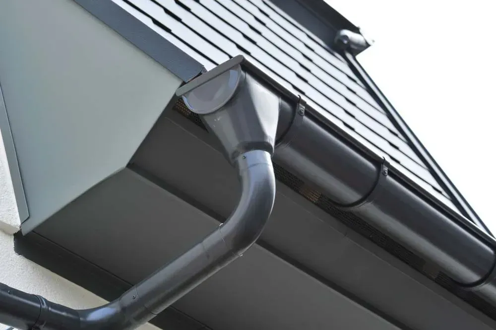 A Close-up View of a Dark Grey Metal Roof Gutter System — Dunnrite Plumbing Services in Cannonvale, QLD