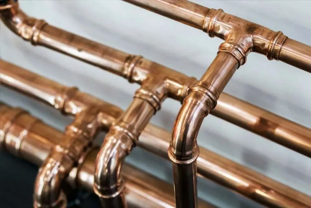 A Cooper Pipe Used for Gas Storing Attached to a White Wall — Dunnrite Plumbing Services in Cannonvale, QLD