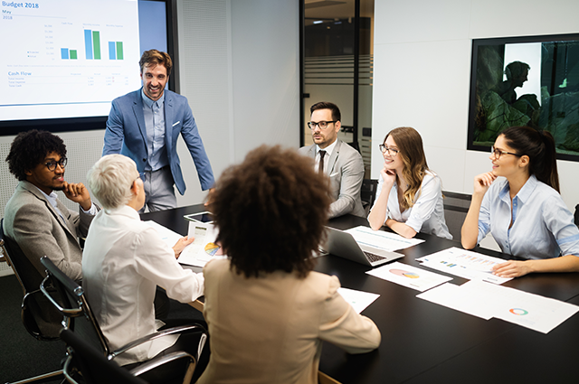 A group of people are sitting around a table in a conference room.