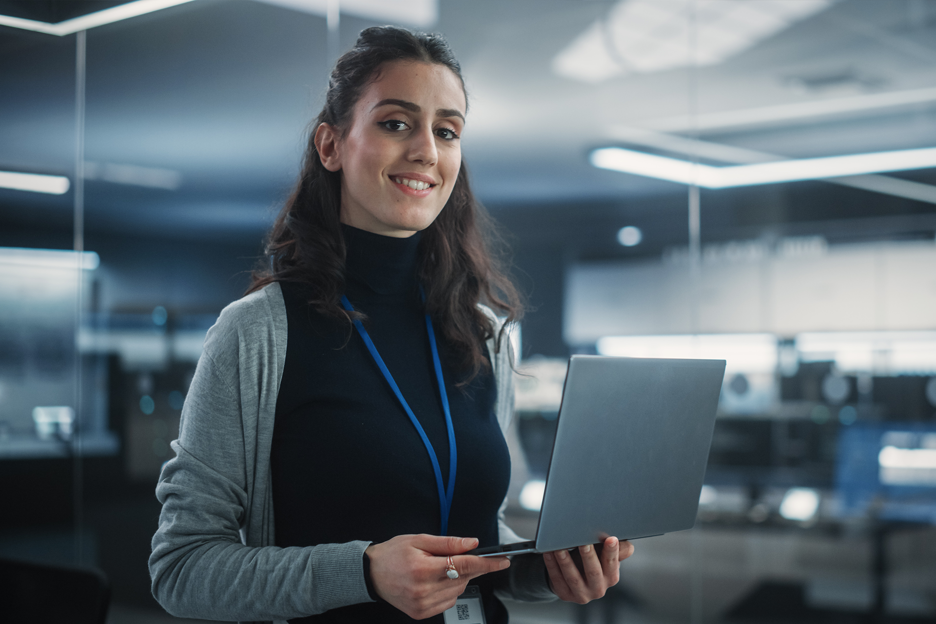 A woman is holding a laptop computer in her hands and smiling.