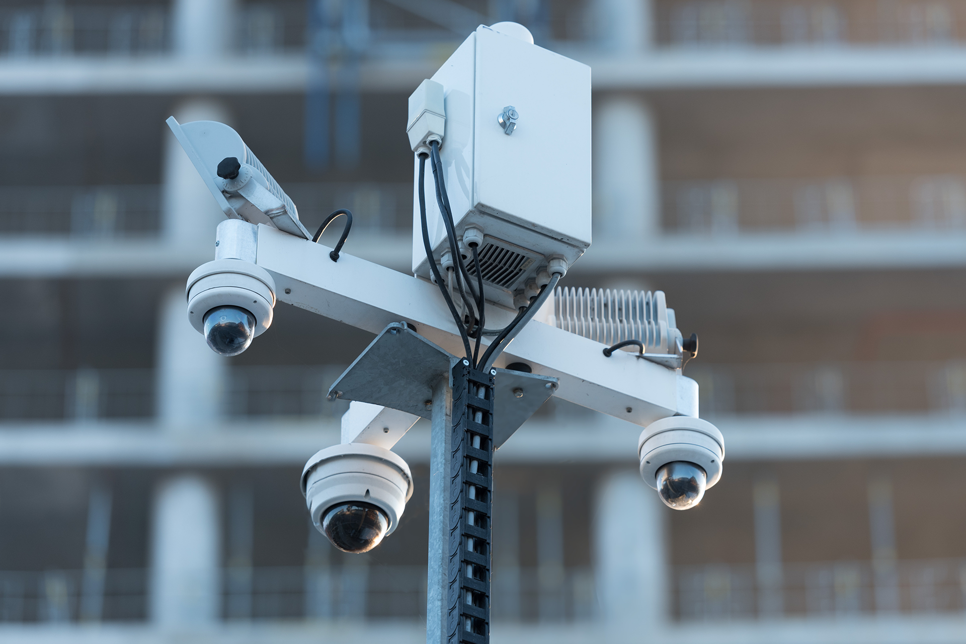 Security cameras on a pole in front of a building.