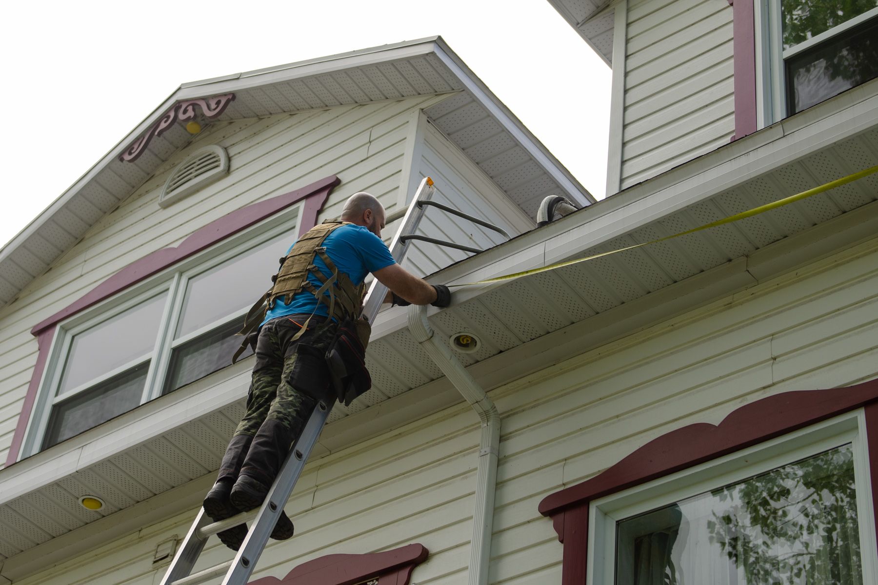 Un homme sur une échelle mesurant le toit d'une maison
