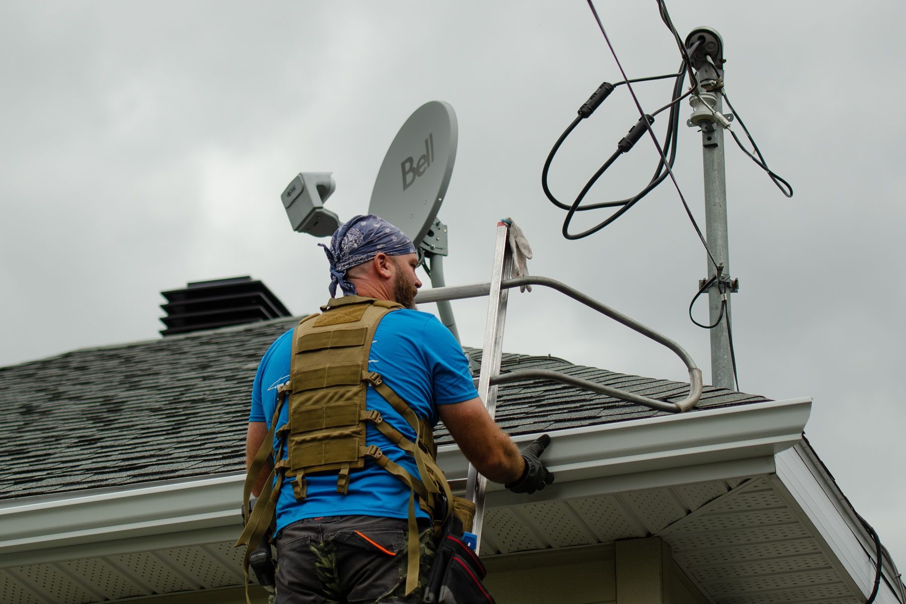 Un homme travaille sur le toit d'une maison avec une antenne parabolique dessus.