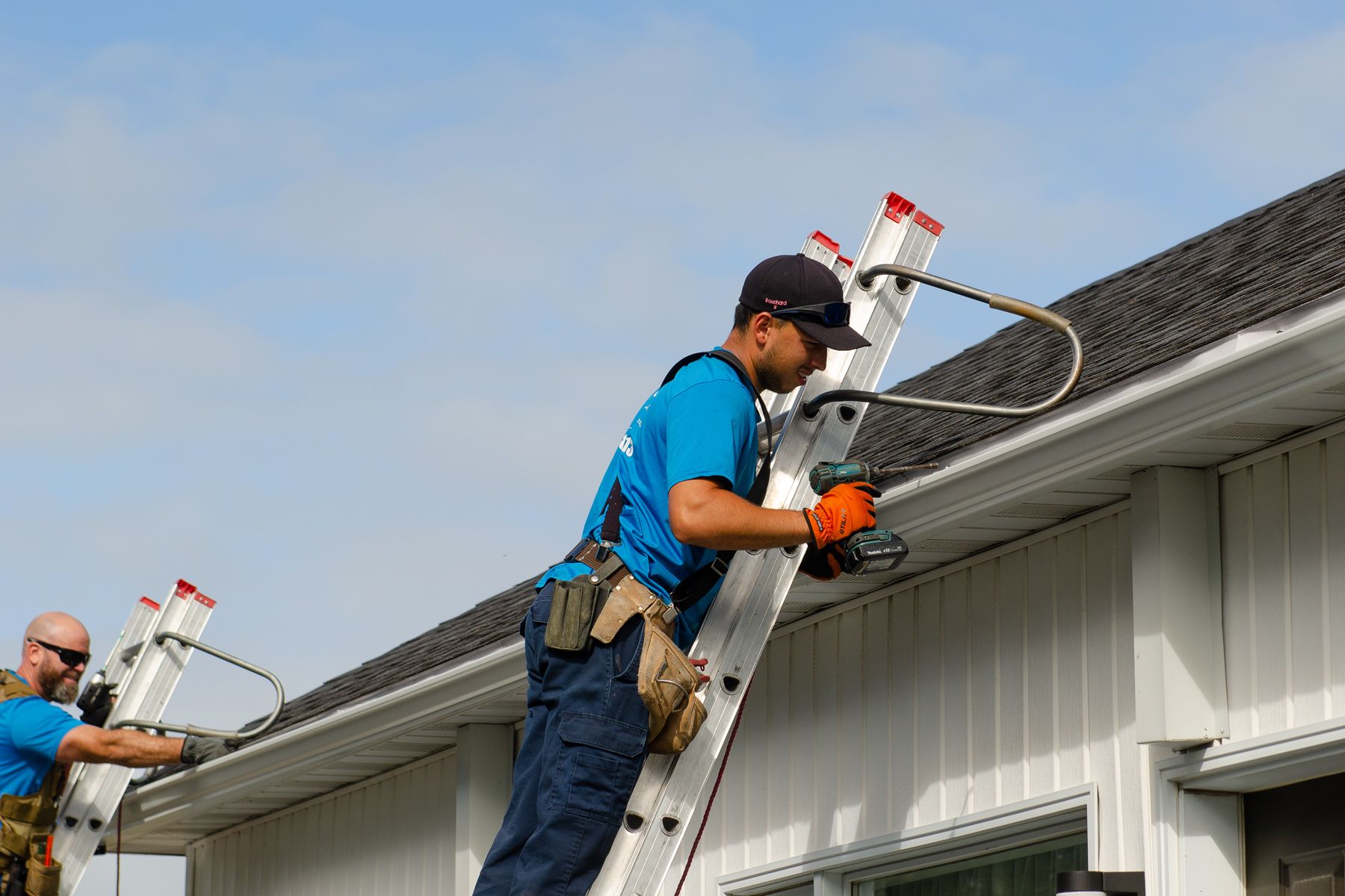 Un groupe d'hommes travaillent sur le toit d'une maison.