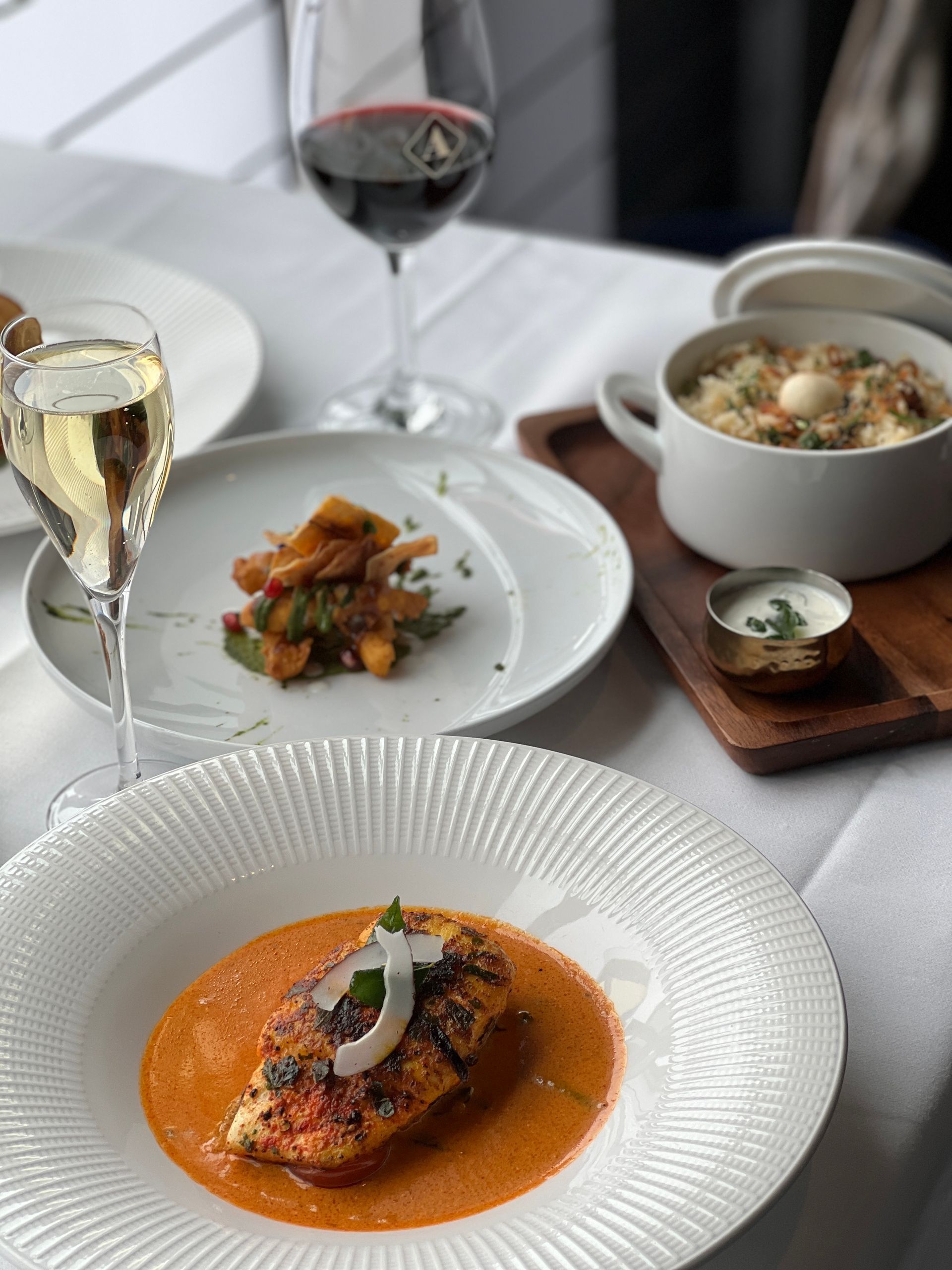 A table topped with plates of food and wine glasses.