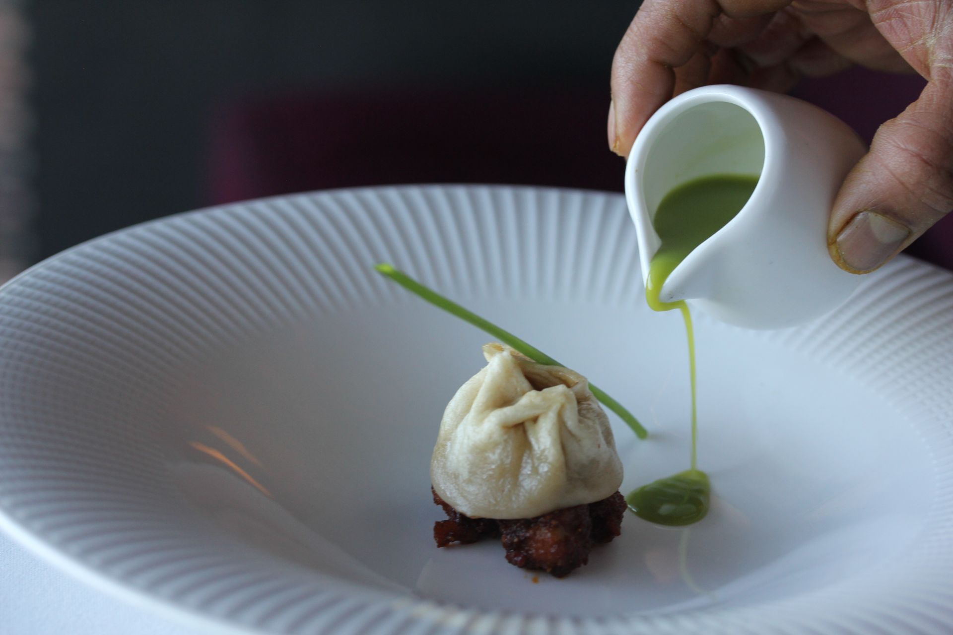 A person pouring green sauce on a plate of food