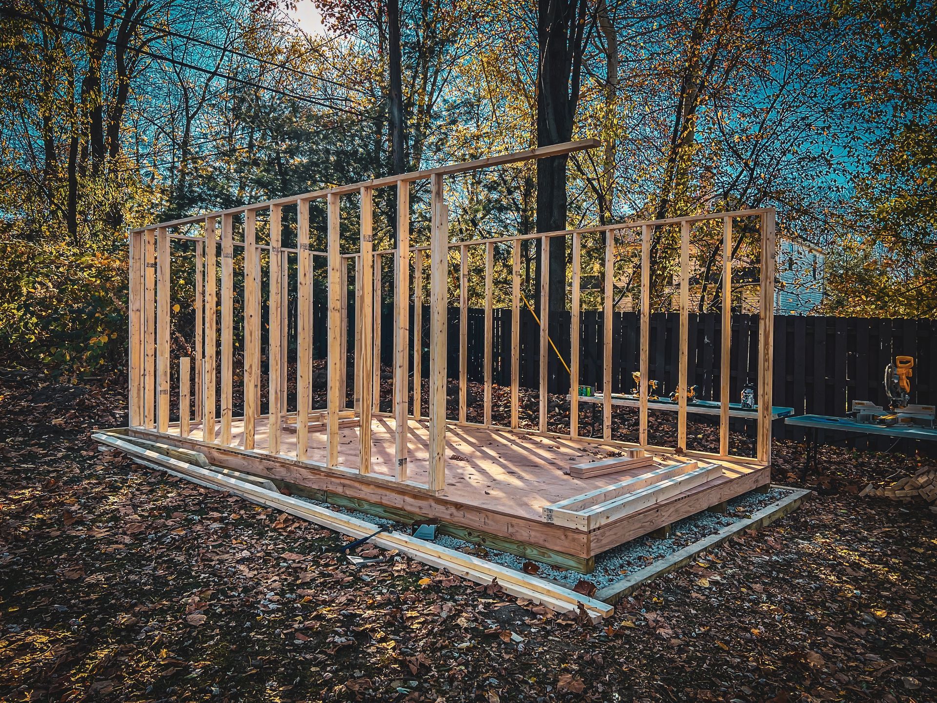 Partially built wooden house frame on a foundation in a wooded lot