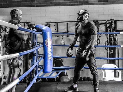 Two men are boxing in a boxing ring in a gym.