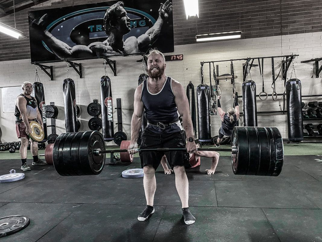 A man is lifting a barbell in a gym.