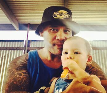 A man is holding a baby who is eating a carrot.