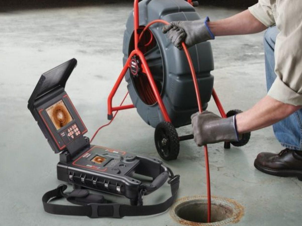 Worker using a drain inspection camera to inspect a sewer manhole