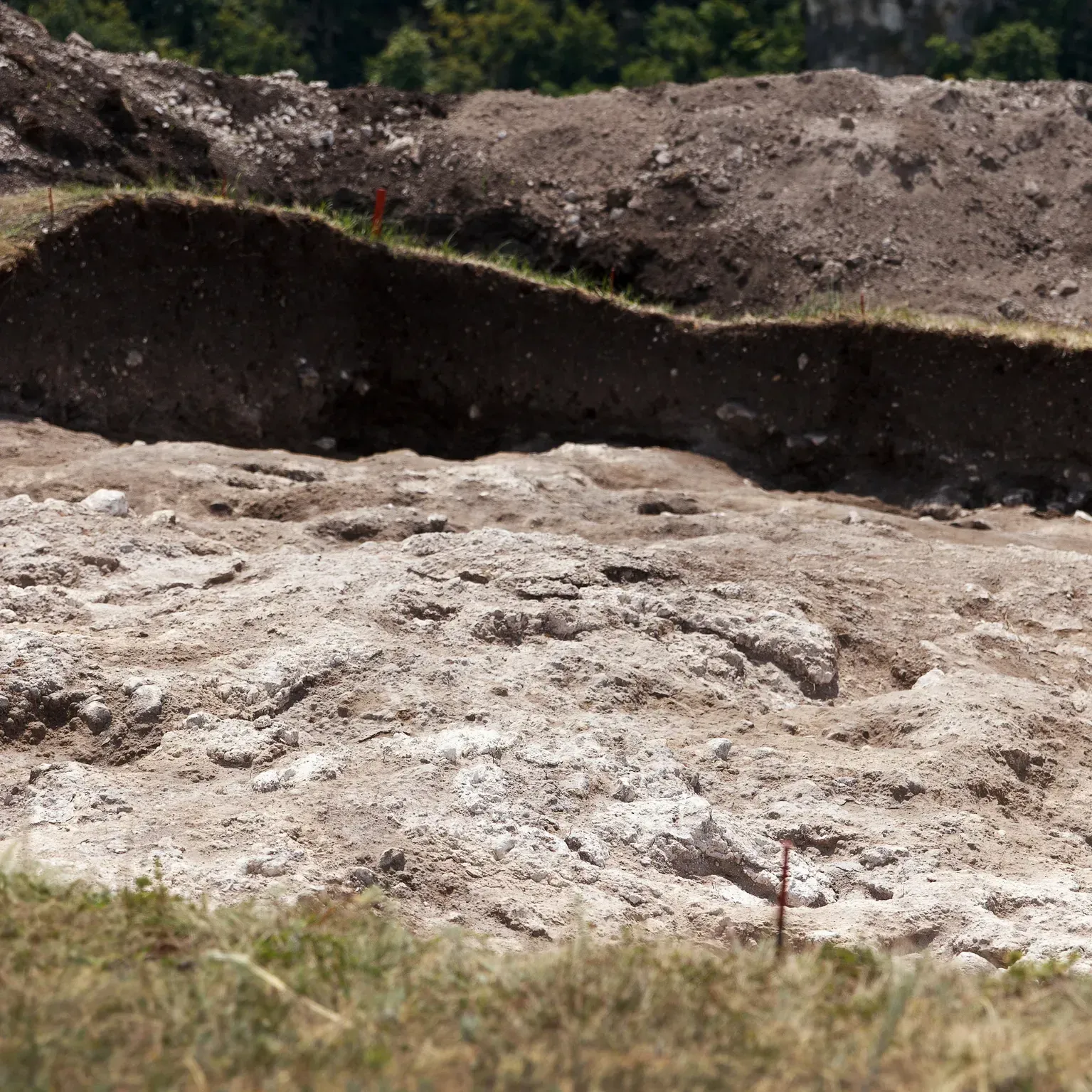Layered soil and rock embankment with a rough, eroded surface in an outdoor landscape.