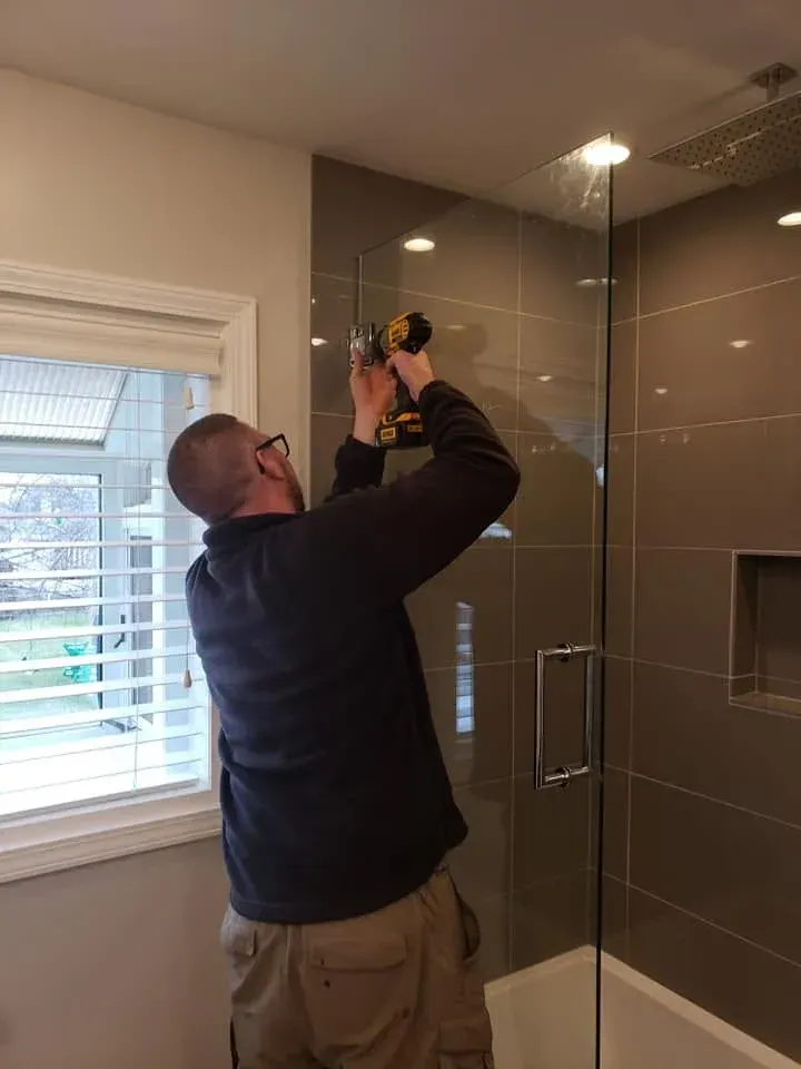 Glass Specialists technician anchoring frameless shower door hardware during a bathroom installation