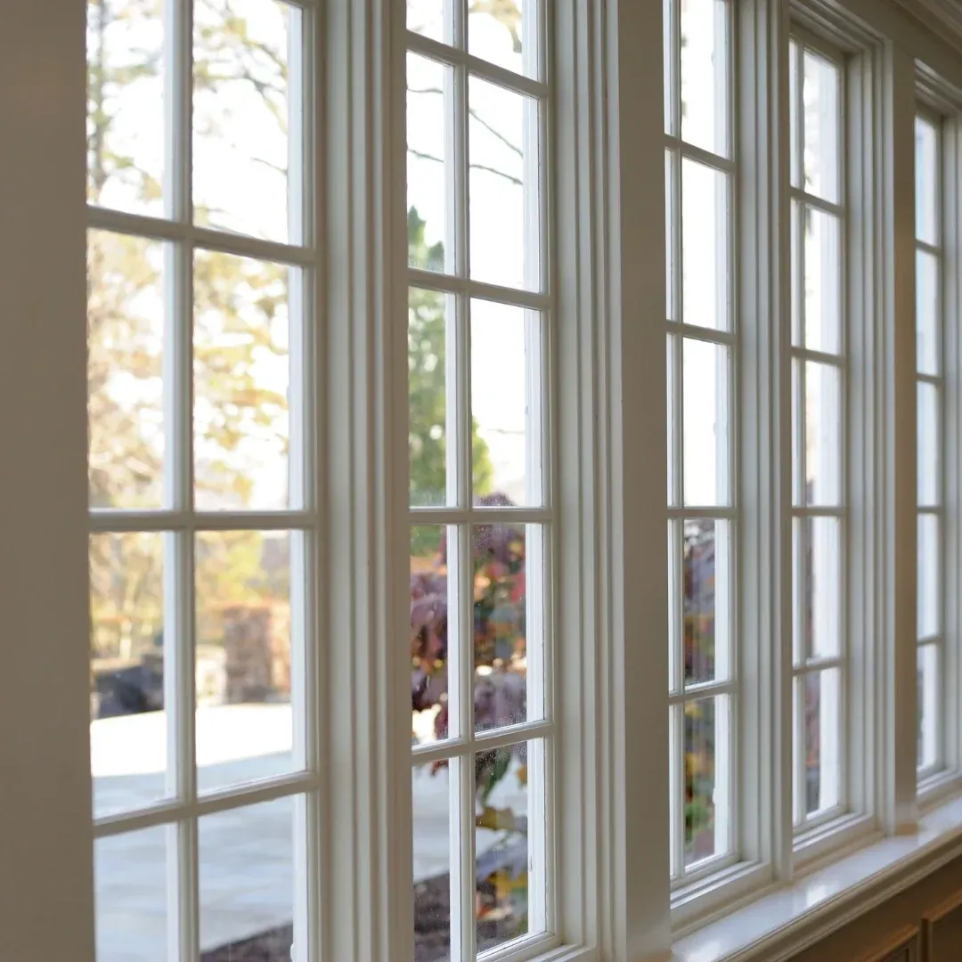 Sunlit white-framed window panes overlooking a blurred outdoor scene