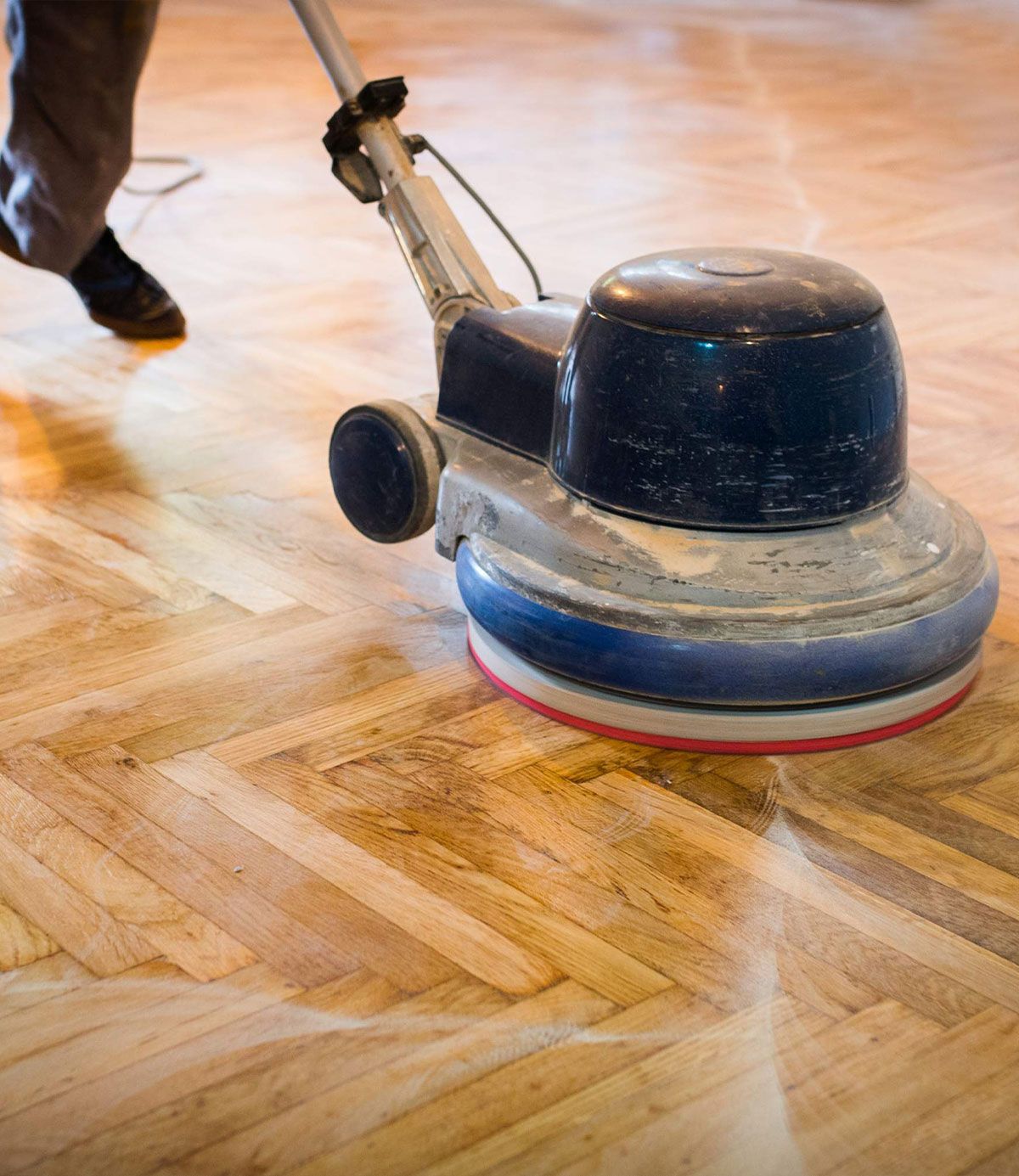 A person is polishing a wooden floor with a machine.