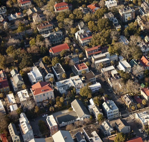 Aerial view of a neighborhood with various houses and buildings, featuring red and white roofs, and green trees. Aerial view of a neighborhood with various houses and buildings, featuring red and white roofs, and green trees.