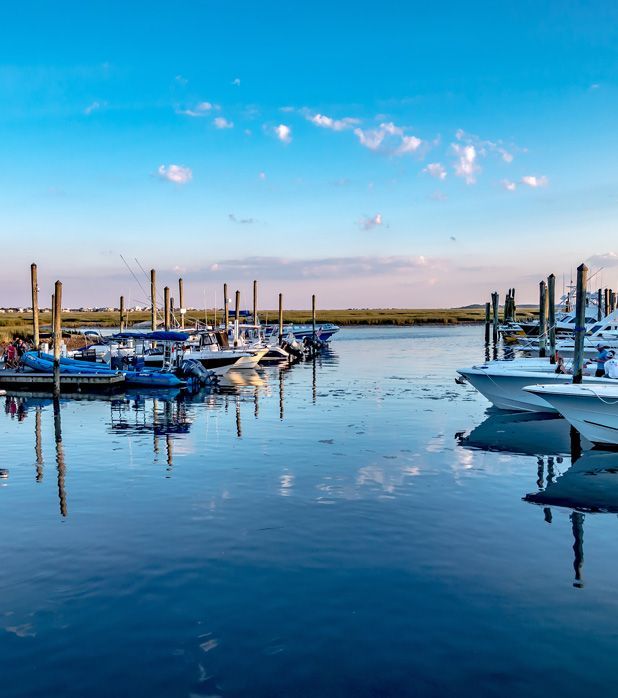 A calm marina at sunset with boats moored along wooden pilings under a clear blue sky. A calm marina at sunset with boats moored along wooden pilings under a clear blue sky.