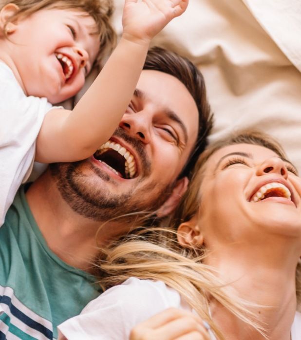 A family laughing together while lying down, viewed from above. A family laughing together while lying down, viewed from above.