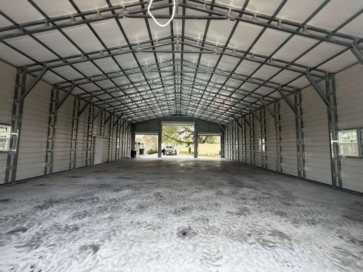 Empty metal warehouse with concrete floor and open front doors letting in daylight