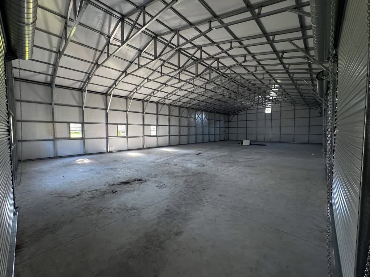 Empty metal warehouse interior with concrete floor and corrugated walls under skylights