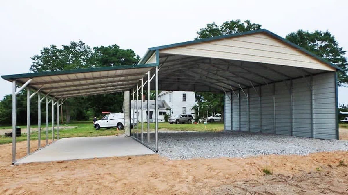 Covered carports with metal roofs and gravel pads beside a white house on a rural lot