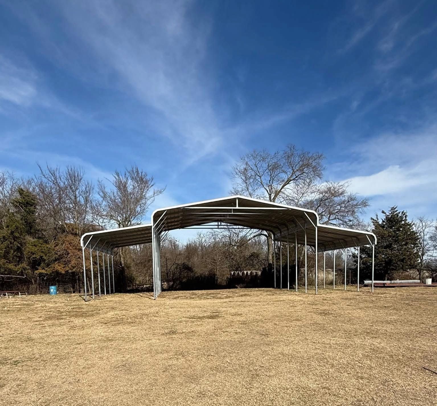 Outdoor pavilion with a white canopy on a grassy field under a blue sky
