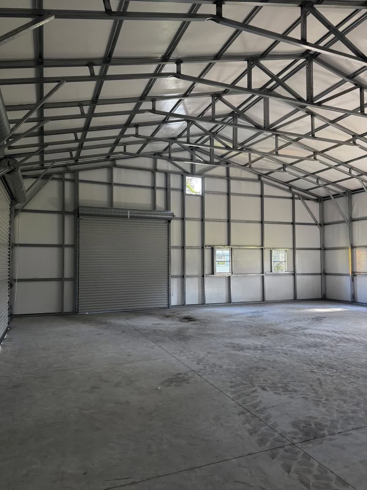 Empty metal-framed warehouse interior with concrete floor and small windows
