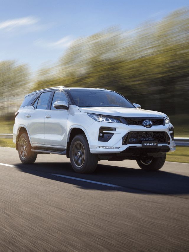 SUV Toyota branca trafegando em uma estrada, com árvores ao fundo, durante o dia.