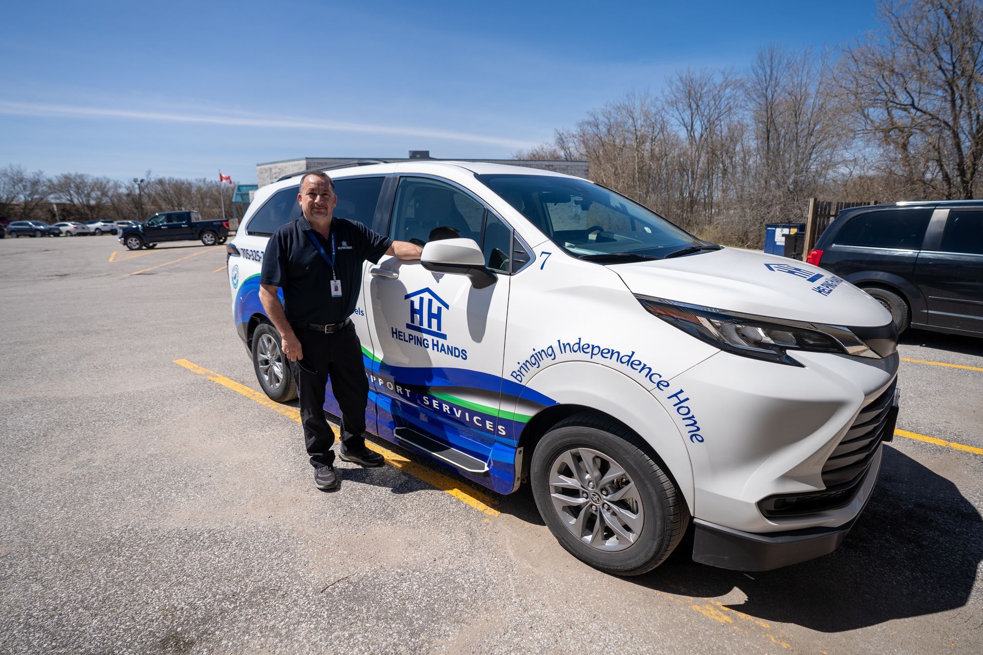 A man is standing next to a white van in a parking lot.