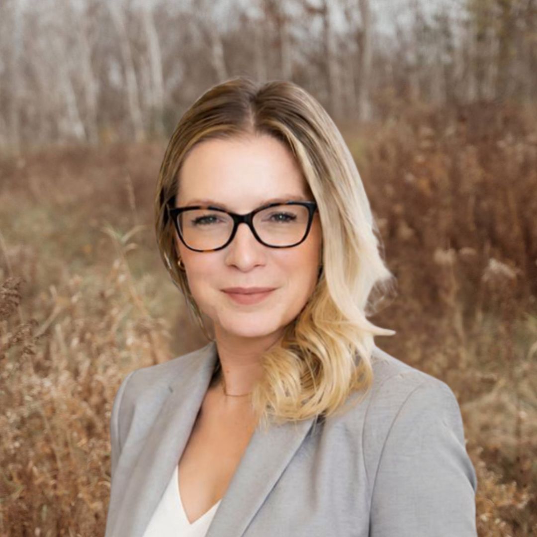 View Bio A woman wearing glasses and a black jacket is smiling for the camera.