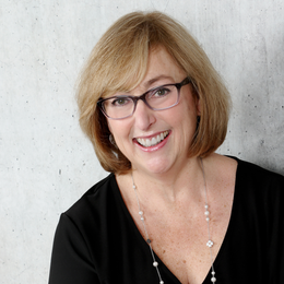 The woman is wearing a black shirt and smiling for the camera.