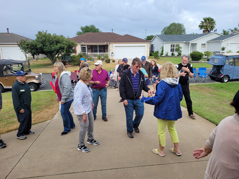 A group of people are dancing on a sidewalk in front of a house.